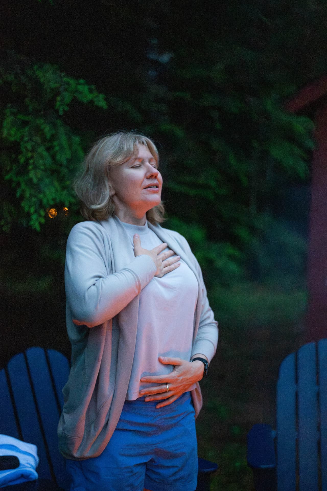Marina breathing calmly at dusk with one hand on her heart and one on her belly